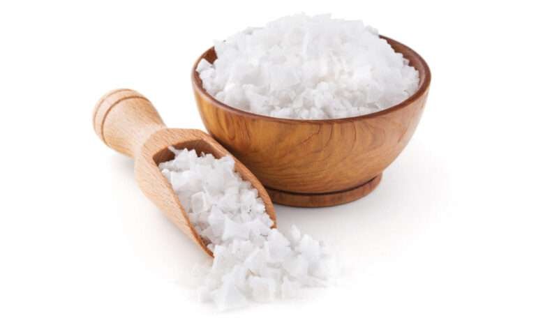 Wooden bowl and scoop with flaky sea salt.
